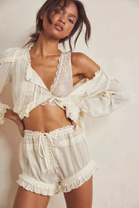 Embrace timeless elegance with the Florence Bed Jacket Set, designed for sophisticated comfort. The structured bed jacket features front tie closures, pleated details, banded trumpet sleeves, and delicate embroidery, offering a refined vintage appeal. Coordinating button-front shorts include a drawstring waist, ruffle trimming, pleated accents, and an embroidered curved hem, ensuring an effortless, flattering fit. This set blends classic style with ease, perfect for lounging with grace and poise.