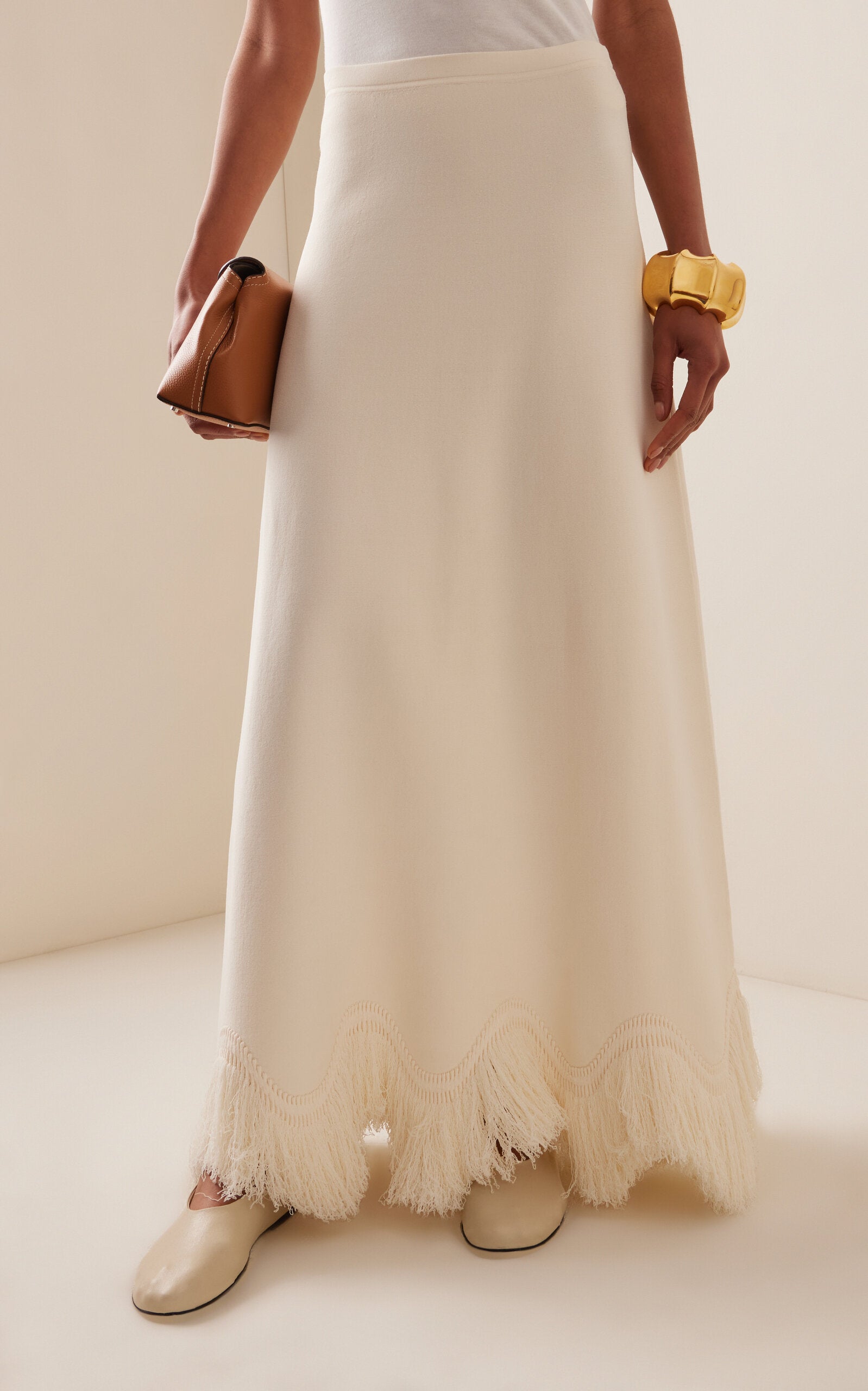 The 'Paulina' skirt offers a graceful A-line shape that gently widens toward its distinctive zig-zag fringe-trimmed hem. Complete the look by pairing it with the coordinating 'Koa' top, which boasts a sleek, sleeveless design accented by a matching zig-zag fringe detail at the hem.