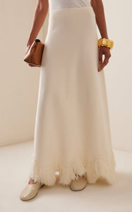 The 'Paulina' skirt offers a graceful A-line shape that gently widens toward its distinctive zig-zag fringe-trimmed hem. Complete the look by pairing it with the coordinating 'Koa' top, which boasts a sleek, sleeveless design accented by a matching zig-zag fringe detail at the hem.