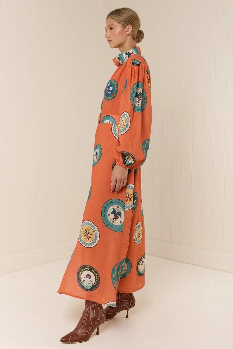 The Noddy Dress in Orange Plates by Palm Noosa showcases a refined midi silhouette crafted from 100% premium linen. Its relaxed fit is complemented by elegant blouson sleeves with elasticated cuffs, a sleek stand collar, and a button-front design. A matching buckle belt allows you to define your waist gracefully, enhancing the dress’s flattering drape. Perfect for an effortless yet polished look, this dress combines comfort and style with sophisticated ease. Please consult our size guide for the best fit.