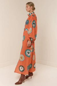 The Noddy Dress in Orange Plates by Palm Noosa showcases a refined midi silhouette crafted from 100% premium linen. Its relaxed fit is complemented by elegant blouson sleeves with elasticated cuffs, a sleek stand collar, and a button-front design. A matching buckle belt allows you to define your waist gracefully, enhancing the dress’s flattering drape. Perfect for an effortless yet polished look, this dress combines comfort and style with sophisticated ease. Please consult our size guide for the best fit.