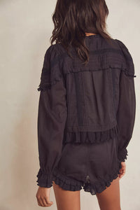 Experience timeless elegance with the Florence Set in Black, designed for both comfort and style. The structured bed jacket features front tie closures, delicate pleated piecing, and banded trumpet sleeves accented by intricate embroidery and ruffle trim. Coordinating shorts offer a drawstring waist for a customizable fit, complemented by ruffle details, pleated patterns, and embroidered accents with a graceful curved hem. Perfect for lounging with refined sophistication.
