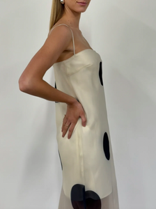 The Mila Maxi Dress in Ivory Polka by Nicole features sheer organza adorned with striking polka dots, shaping a sleek column silhouette. Its half-lined design and elasticated back ensure comfort and adaptability, while the option to wear it with or without straps provides versatile styling choices perfect for refined occasions.