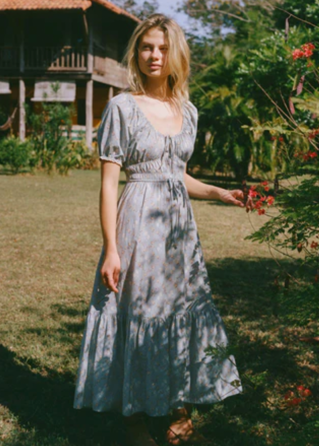 The Brynne Dress in the seasonal Pansy Blues print by Christy Dawn combines delicate femininity with adjustable comfort. It features a low scoop neckline complemented by a drawstring tie at both the neck and waist, allowing a custom fit that enhances your silhouette. Elasticated seams ensure ease of movement, making this dress as practical as it is stylish for versatile wear throughout the season.