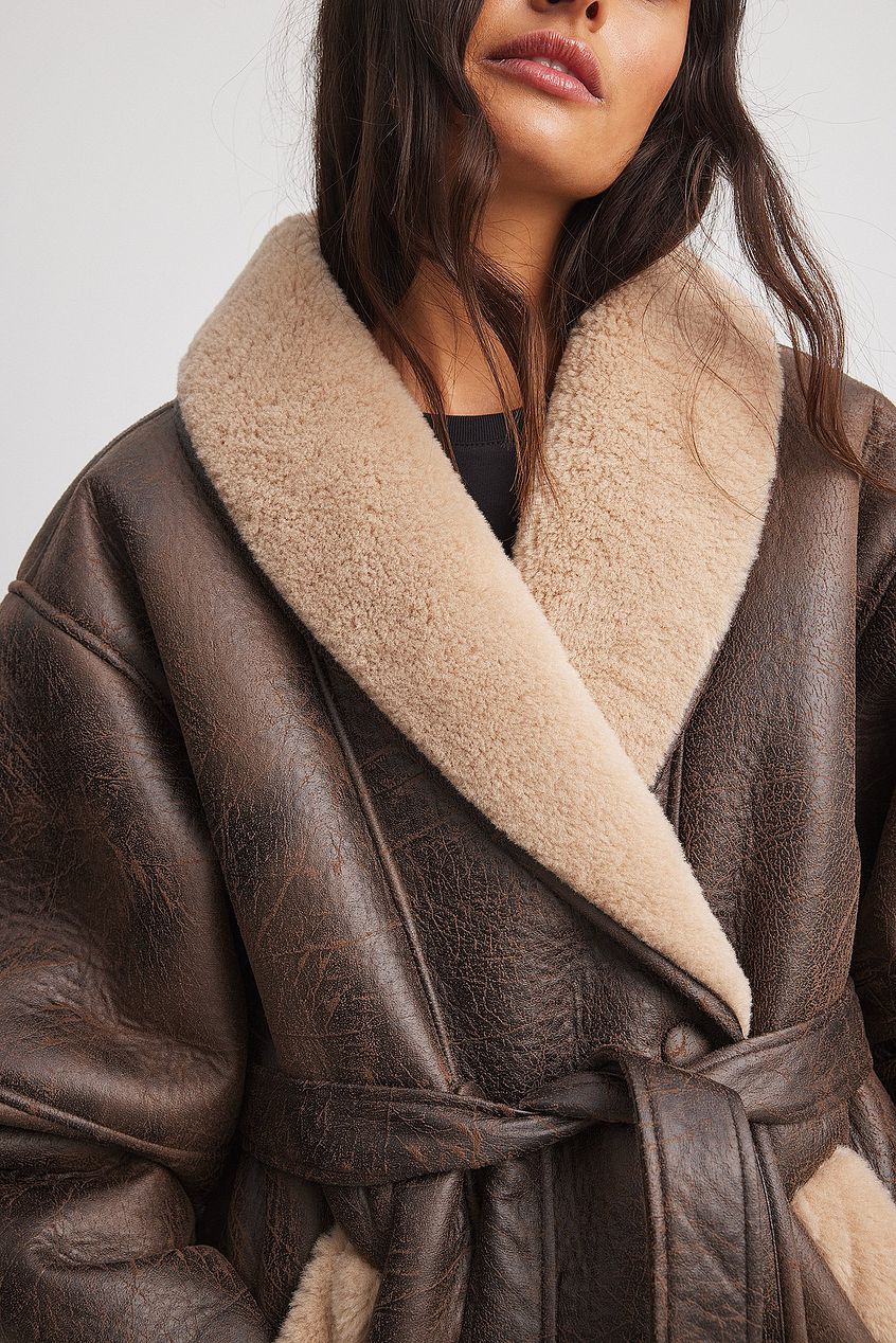 Indulge in luxury with the Belted Detail Shearling Jacket. Crafted from padded faux fur, this oversized jacket exudes sophistication with its lapel neckline and open slant pockets. The removable self-tie belt and single-breasted button closure add a touch of elegance. Available in rich brown, elevate your style today.