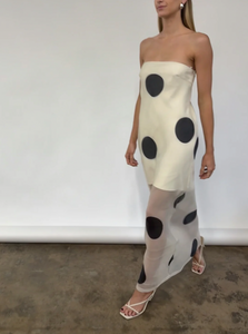 The Mila Maxi Dress in Ivory Polka by Nicole features sheer organza adorned with striking polka dots, shaping a sleek column silhouette. Its half-lined design and elasticated back ensure comfort and adaptability, while the option to wear it with or without straps provides versatile styling choices perfect for refined occasions.