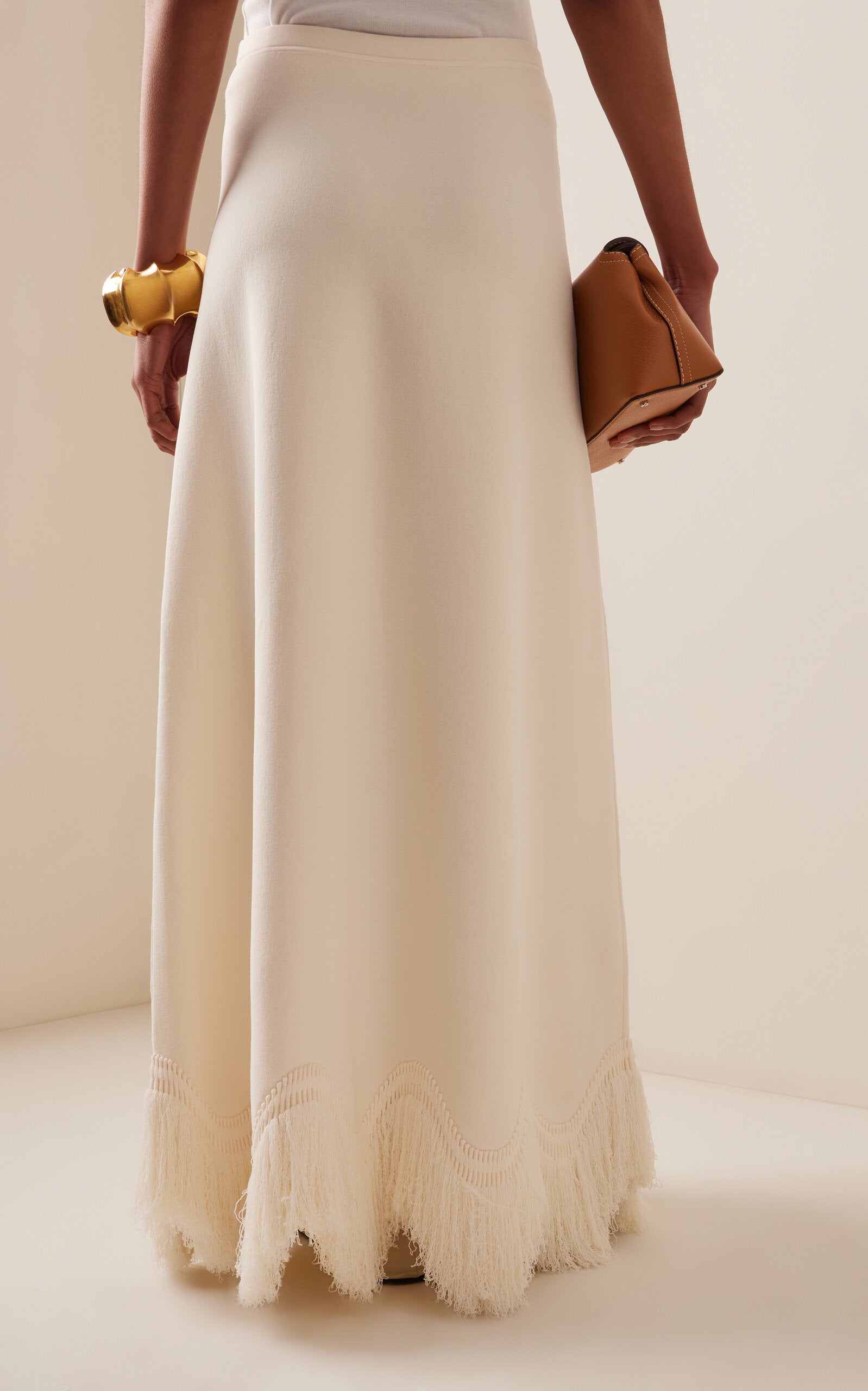 The 'Paulina' skirt offers a graceful A-line shape that gently widens toward its distinctive zig-zag fringe-trimmed hem. Complete the look by pairing it with the coordinating 'Koa' top, which boasts a sleek, sleeveless design accented by a matching zig-zag fringe detail at the hem.