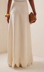 The 'Paulina' skirt offers a graceful A-line shape that gently widens toward its distinctive zig-zag fringe-trimmed hem. Complete the look by pairing it with the coordinating 'Koa' top, which boasts a sleek, sleeveless design accented by a matching zig-zag fringe detail at the hem.