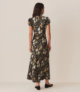 Crafted from a drapey silk-viscose twill, the Merla Dress by Doen in Sweet Anemone boasts an elegant bias cut that flatters the silhouette. Inspired by Art Deco motifs, this dress features a refined high neck and delicate short puffed sleeves, blending timeless style with modern sophistication. Perfect for occasions that call for understated glamour.