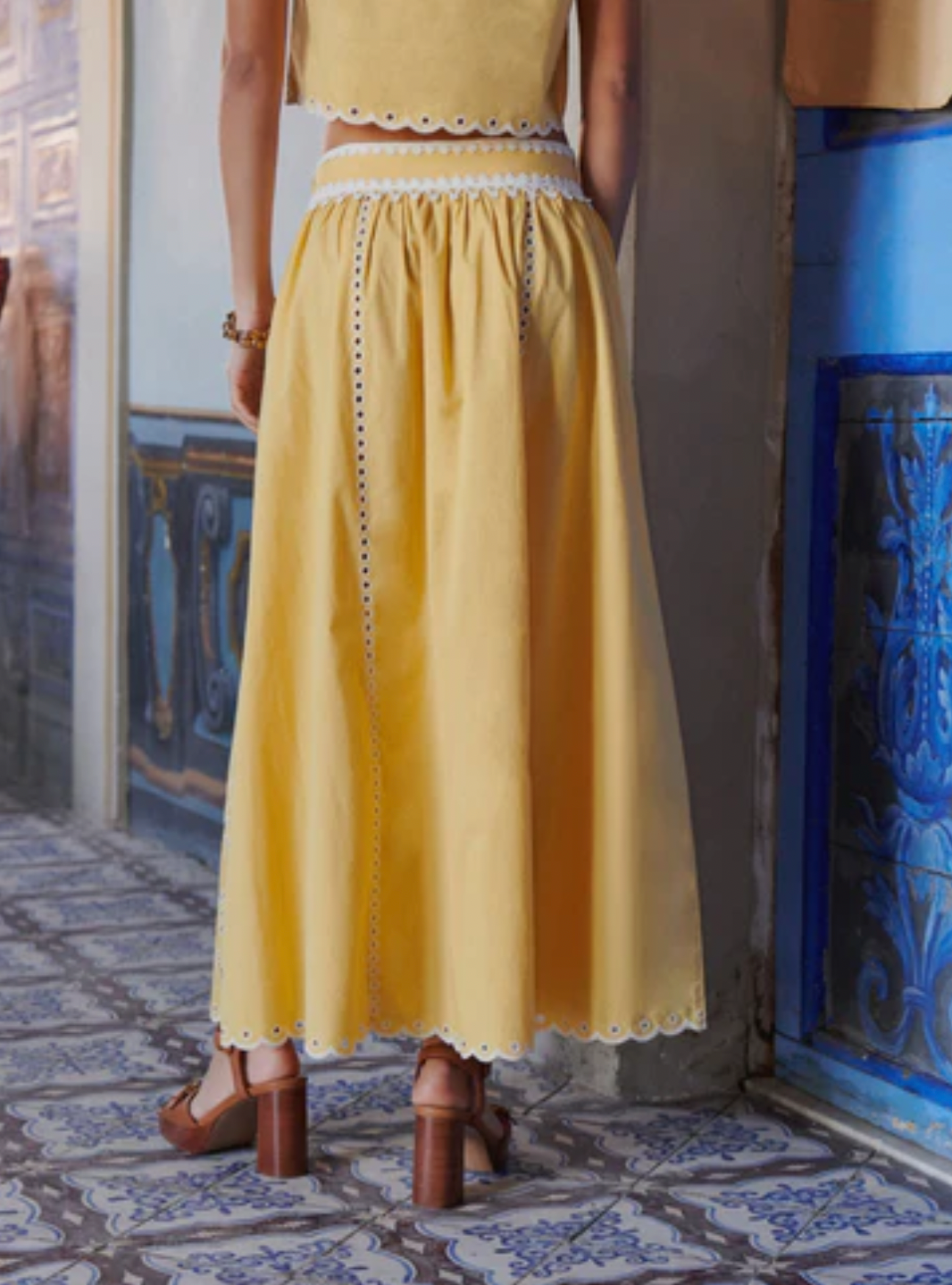 The Tiffany Set combines a vibrant skirt and top, expertly crafted to elevate your seasonal wardrobe. The skirt features intricate openwork patterns and a scalloped hem, enhanced with modernized iconic embroidery using inlaid guipure, adding refined elegance. The top complements with its sunny tone and delicate embroidery, versatile enough for pairing with high-waisted jeans or the matching skirt for a coordinated, feminine ensemble. 