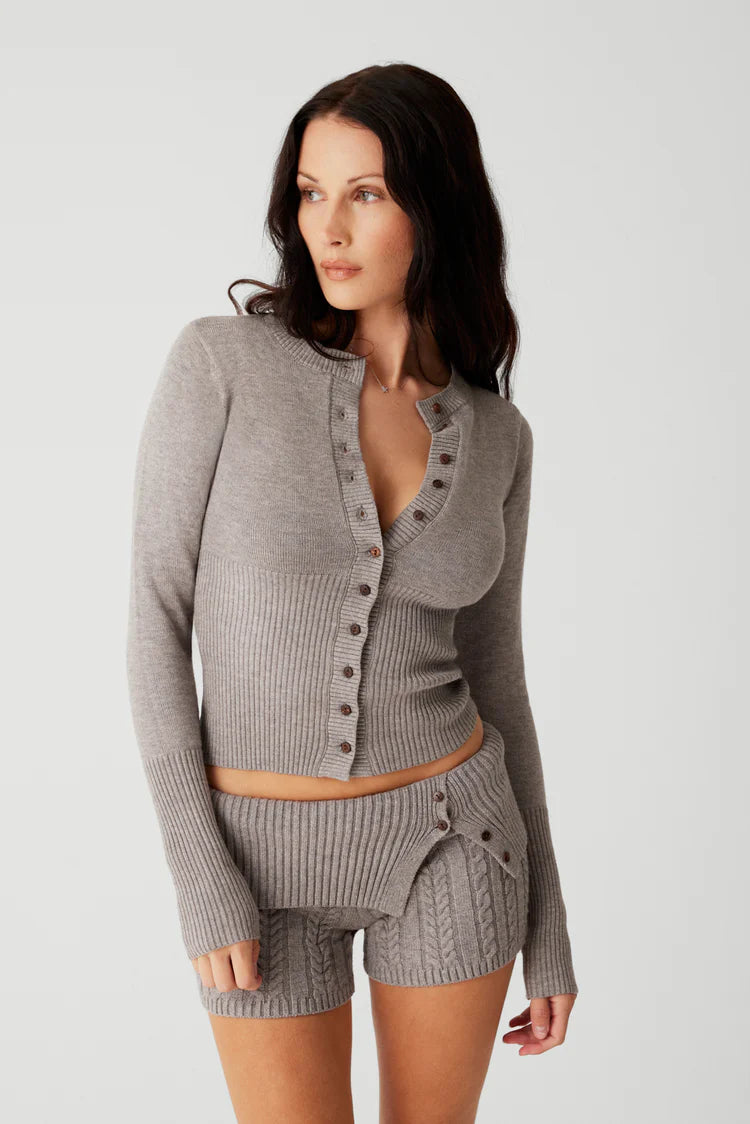 Indulge in luxurious warmth this season with the Lenon Cloud Knit Button Up Cardigan by Frankies Bikinis. The signature cloud knit fabric creates a soft and cozy feel, while the functional buttons and exaggerated cuffs add an elegant touch. Complete with ribbing on the waist and cuffs, the Lenon cardigan is the perfect statement piece for your winter wardrobe.