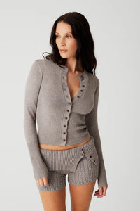 Indulge in luxurious warmth this season with the Lenon Cloud Knit Button Up Cardigan by Frankies Bikinis. The signature cloud knit fabric creates a soft and cozy feel, while the functional buttons and exaggerated cuffs add an elegant touch. Complete with ribbing on the waist and cuffs, the Lenon cardigan is the perfect statement piece for your winter wardrobe.