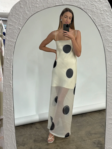 The Mila Maxi Dress in Ivory Polka by Nicole features sheer organza adorned with striking polka dots, shaping a sleek column silhouette. Its half-lined design and elasticated back ensure comfort and adaptability, while the option to wear it with or without straps provides versatile styling choices perfect for refined occasions.
