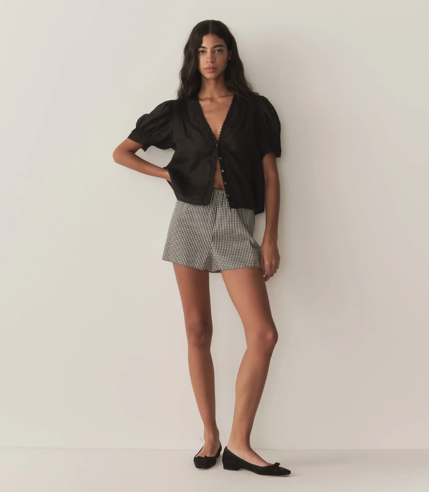 Crafted from lightweight semi-sheer ramie, the Brigitta Top by Doen draws inspiration from Victorian fashion with its plunging V-neckline and delicate lace detailing. The short puffed sleeves feature clustered pintucks, while a line of starburst buttons runs down the center front, adding refined charm. Versatile in style, it can be worn loose for an airy feel or tucked into high-waisted jeans for a polished look.