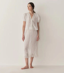 Crafted from lightweight semi-sheer ramie, the Brigitta Top by Doen draws inspiration from Victorian fashion with its plunging V-neckline and delicate lace detailing. The short puffed sleeves feature clustered pintucks, while a line of starburst buttons runs down the center front, adding refined charm. Versatile in style, it can be worn loose for an airy feel or tucked into high-waisted jeans for a polished look.