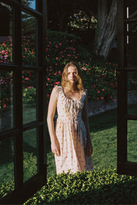 Inspired by Edwardian corsets, the Eliana Dress combines classic sophistication with contemporary ease. Made from 100% organic cotton, this sleeveless midi features an exaggerated wide scoop neckline adorned with contrasting eyelet trim and soft ruffles. A half-functional front button placket and subtle micro pintucks at the bust provide elegant accents, while the lace-up back creates a striking, form-fitting silhouette. 