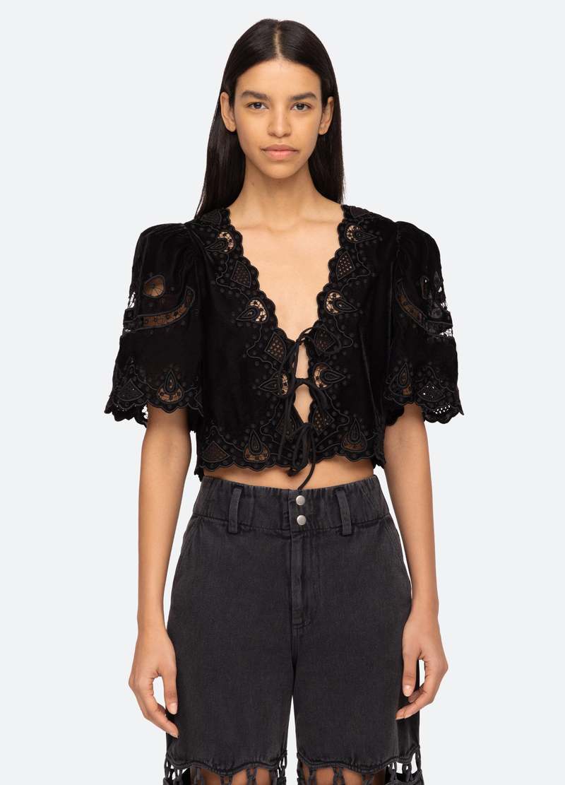 Introducing the Eliana Top by SEA, a luxurious piece adorned with intricate embroidery and a playful tie front. Its short, flowy sleeves add a touch of femininity. Elevate your style with this exclusive top that boasts elegance and sophistication.
