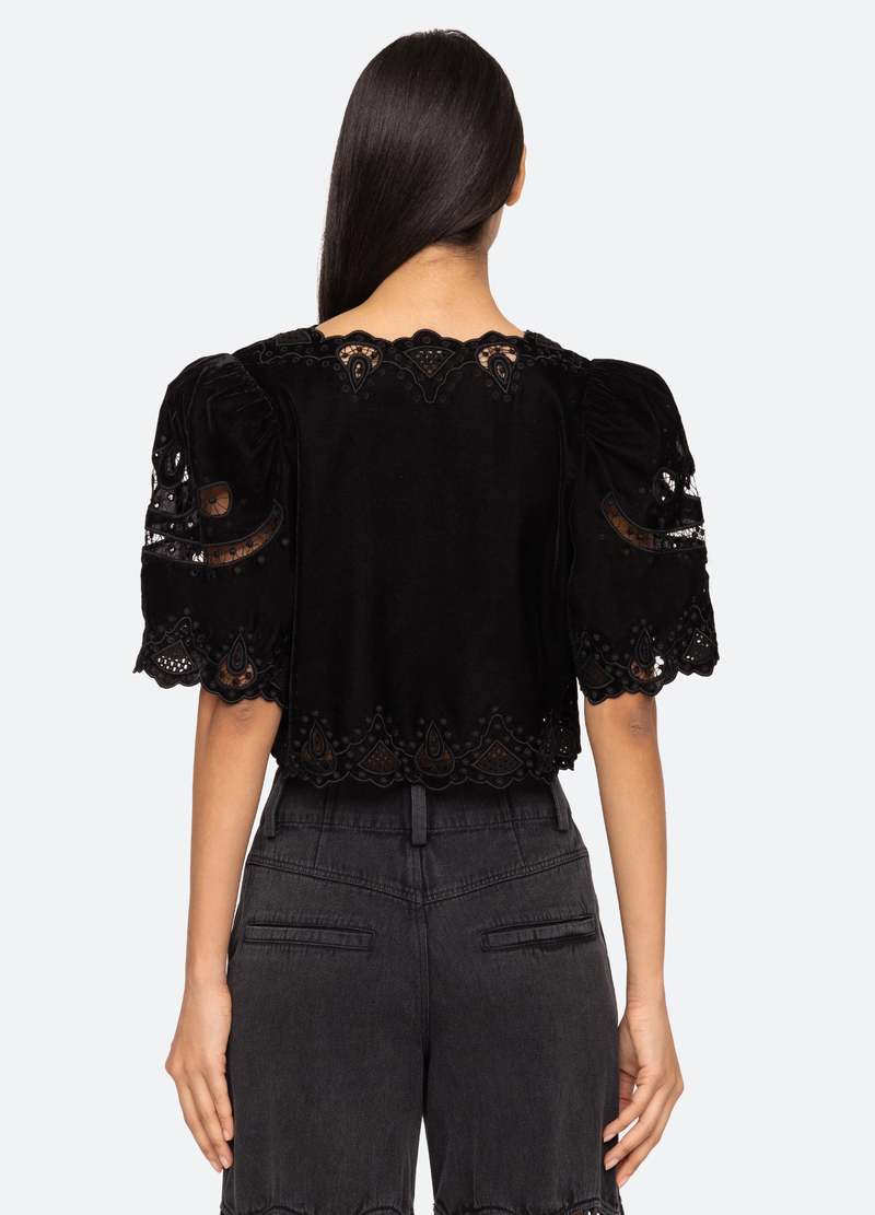 Introducing the Eliana Top by SEA, a luxurious piece adorned with intricate embroidery and a playful tie front. Its short, flowy sleeves add a touch of femininity. Elevate your style with this exclusive top that boasts elegance and sophistication.