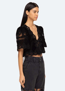 Introducing the Eliana Top by SEA, a luxurious piece adorned with intricate embroidery and a playful tie front. Its short, flowy sleeves add a touch of femininity. Elevate your style with this exclusive top that boasts elegance and sophistication.
