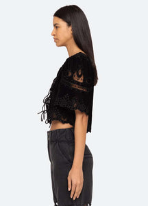 Introducing the Eliana Top by SEA, a luxurious piece adorned with intricate embroidery and a playful tie front. Its short, flowy sleeves add a touch of femininity. Elevate your style with this exclusive top that boasts elegance and sophistication.