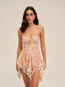 Elevate your summer wardrobe with the Elea Mini Dress, a delicate blend of romance and sophistication. This peach floral mini dress features structured underwire cups and a boned bodice for refined support and shape. Its multi-layered asymmetrical skirt gathers gracefully, ending with lace ruffles that add a subtle touch of elegance. Perfect for warm days and special occasions, the Elea Mini Dress offers a flattering silhouette that embodies effortless femininity.