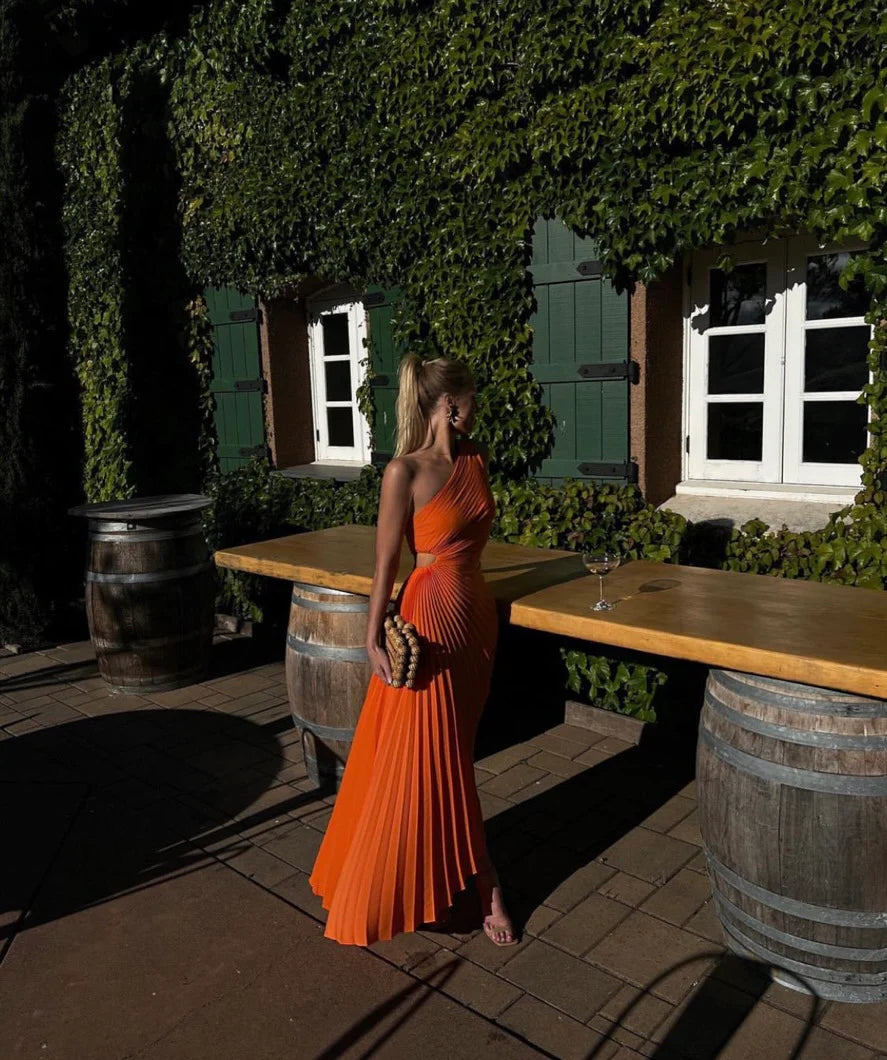 The Delfina Dress by ALC features an elegant one-shoulder design with a subtle side cut-out that adds a modern touch. Crafted from flowy pleated satin, its asymmetrical hem enhances movement and grace, making it perfect for sophisticated occasions.