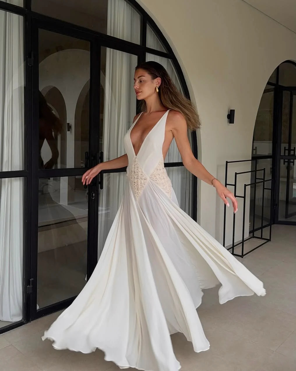The Lavinia Dress by Arcina Ori exudes effortless elegance with its plunging V-neckline adorned by delicate lace accents. Adjustable straps converge into a graceful open back, enhancing its feminine appeal. Crafted from lightweight georgette, the ruched skirt flows gently, offering a fluid silhouette that moves with ease. Ideal for intimate gatherings or romantic moments, Lavinia blends sophistication with comfort for the modern muse.