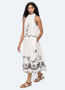 The Kingsley embroidered tank dress in cream by SEA NY showcases intricate embroidery throughout its design, offering a refined and elegant appeal. It features a high neckline that adds a sophisticated touch, complemented by a delicate back bow tie for adjustable fit and added charm. The scalloped hemline enhances the dress's feminine silhouette, making it an exceptional choice for those seeking a polished yet distinctive look.