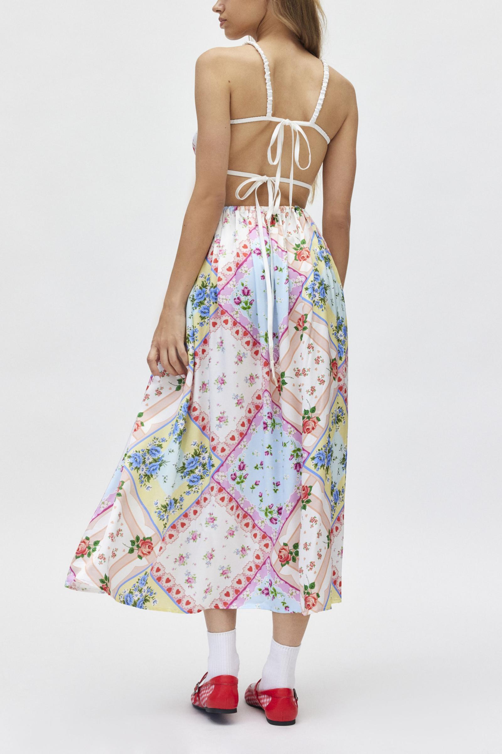 The Cassandra Dress by For Love & Lemons offers a chic and sophisticated look with its midi length, square neckline, and open back design. Its silky, patchwork quilted fabric adds texture and interest, while the fitted bodice with rose detail and double back ties create a flattering silhouette. Perfect for any occasion, with adjustable closures for a customizable fit.