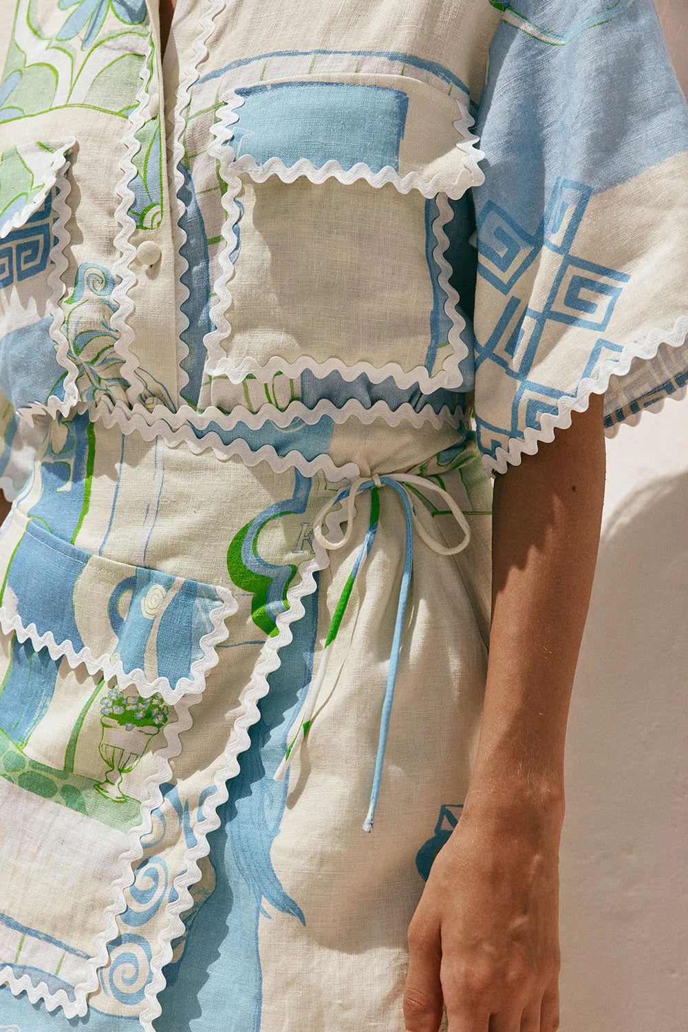 Elevate your style with our Diaz Skirt! Made from premium linen, this mini skirt features charming ric rac trim edges and a wrap panel with a tie at the front for a flattering fit. Large pockets add practicality to this chic piece. Upgrade your wardrobe today!