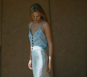 Crafted from sumptuous sandwashed satin, the Elise Top by DÔEN boasts ultra-skinny adjustable spaghetti straps and artful cutouts that sculpt a refined silhouette. Its plunging V-neckline features scalloped edges, enhanced by intricate floral eyelet embroidery and delicate hand-embroidered butterflies at the neckline, back, and hem. Elegant flower-shaped mother-of-pearl buttons complete the design, offering a sophisticated finish suitable for both everyday wear and distinguished events. 