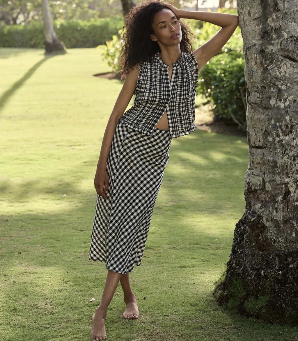 The Elowen Skirt in Marilyn Gingham by Doen offers a refined midi length enhanced by a timeless gingham pattern. Crafted from lightweight fabric, its flowy silhouette ensures comfort without sacrificing style. Versatile enough for casual or formal settings, this skirt pairs seamlessly with diverse tops and accessories, making it a sophisticated staple for any wardrobe seeking effortless elegance.