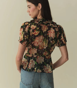 The Alona Top by Doen offers timeless sophistication with its light silk georgette fabric and 1930s-inspired design. Featuring short puffed sleeves and a Peter Pan collar adorned with delicate picot-edged ruffles, this blouse highlights a shirred bust that flows into a breezy, slightly cropped silhouette with a bias-cut hem. Self-covered buttons along the front enhance its refined charm. 