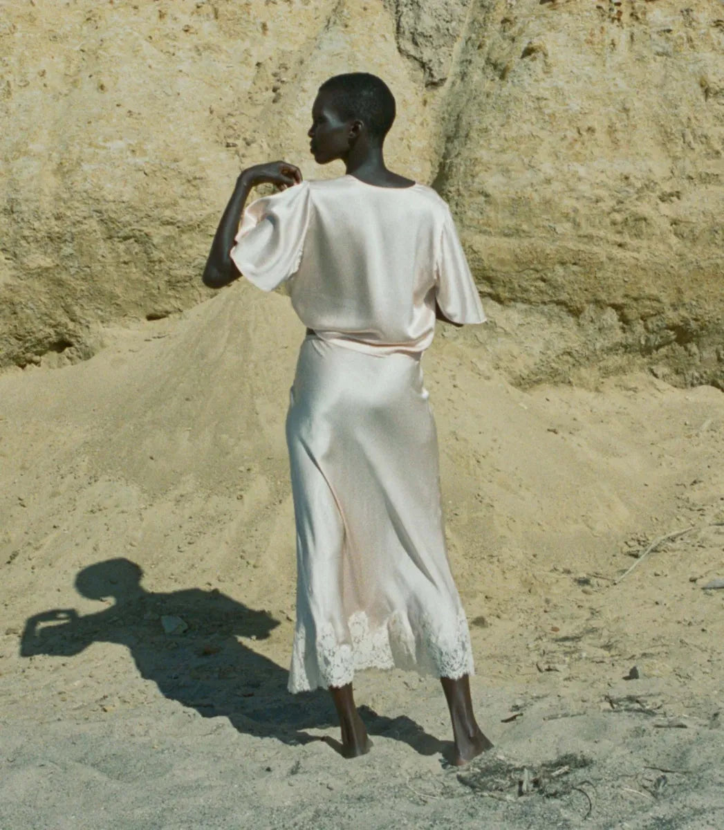 Indulge in timeless elegance with the Elowen Skirt from Doen. This luxurious silk satin skirt features delicate scallop elastic trims and a bias-cut midi design adorned with intricate contrast lace. Its high-waisted silhouette adds a touch of '90s nostalgia, perfect for pairing with the Chantal Top for an elevated matching set. From day to night, embrace sophistication with the Elowen Skirt.