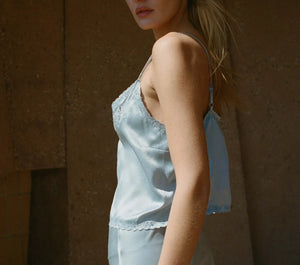 Crafted from sumptuous sandwashed satin, the Elise Top by DÔEN boasts ultra-skinny adjustable spaghetti straps and artful cutouts that sculpt a refined silhouette. Its plunging V-neckline features scalloped edges, enhanced by intricate floral eyelet embroidery and delicate hand-embroidered butterflies at the neckline, back, and hem. Elegant flower-shaped mother-of-pearl buttons complete the design, offering a sophisticated finish suitable for both everyday wear and distinguished events. 