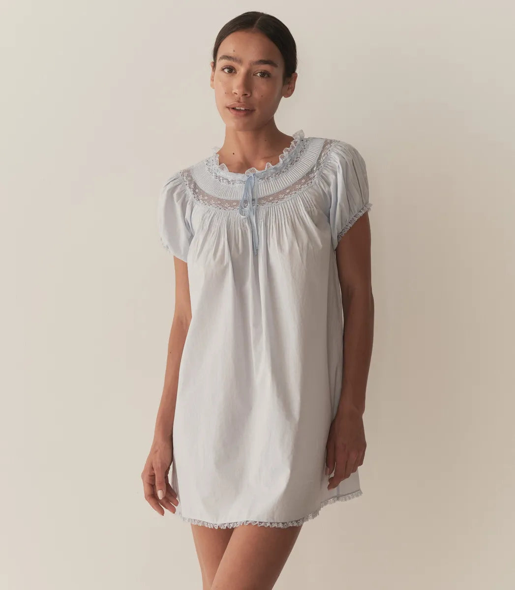 The Daphné Dress by Doen, crafted from crisp organic cotton poplin, offers a refined feminine silhouette with its flattering A-line cut and short puffed sleeves. Featuring delicate floral scallop lace, pintuck accents, and a grosgrain ribbon tie at the neckline, it balances elegance and detail. The scalloped lace trims on the cuffs and hem provide subtle sophistication, making this mini-length dress ideal for warm weather or casual occasions where comfort and style are paramount.
