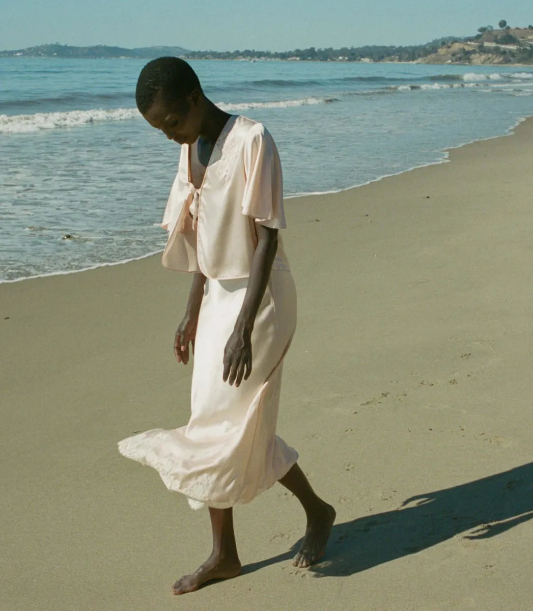 Indulge in timeless elegance with the Elowen Skirt from Doen. This luxurious silk satin skirt features delicate scallop elastic trims and a bias-cut midi design adorned with intricate contrast lace. Its high-waisted silhouette adds a touch of '90s nostalgia, perfect for pairing with the Chantal Top for an elevated matching set. From day to night, embrace sophistication with the Elowen Skirt.