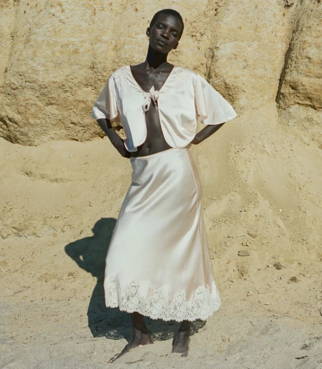 Indulge in timeless elegance with the Elowen Skirt from Doen. This luxurious silk satin skirt features delicate scallop elastic trims and a bias-cut midi design adorned with intricate contrast lace. Its high-waisted silhouette adds a touch of '90s nostalgia, perfect for pairing with the Chantal Top for an elevated matching set. From day to night, embrace sophistication with the Elowen Skirt.