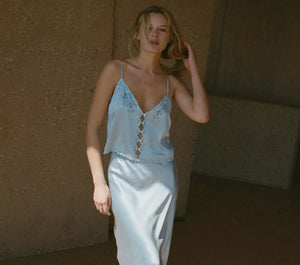Crafted from sumptuous sandwashed satin, the Elise Top by DÔEN boasts ultra-skinny adjustable spaghetti straps and artful cutouts that sculpt a refined silhouette. Its plunging V-neckline features scalloped edges, enhanced by intricate floral eyelet embroidery and delicate hand-embroidered butterflies at the neckline, back, and hem. Elegant flower-shaped mother-of-pearl buttons complete the design, offering a sophisticated finish suitable for both everyday wear and distinguished events. 