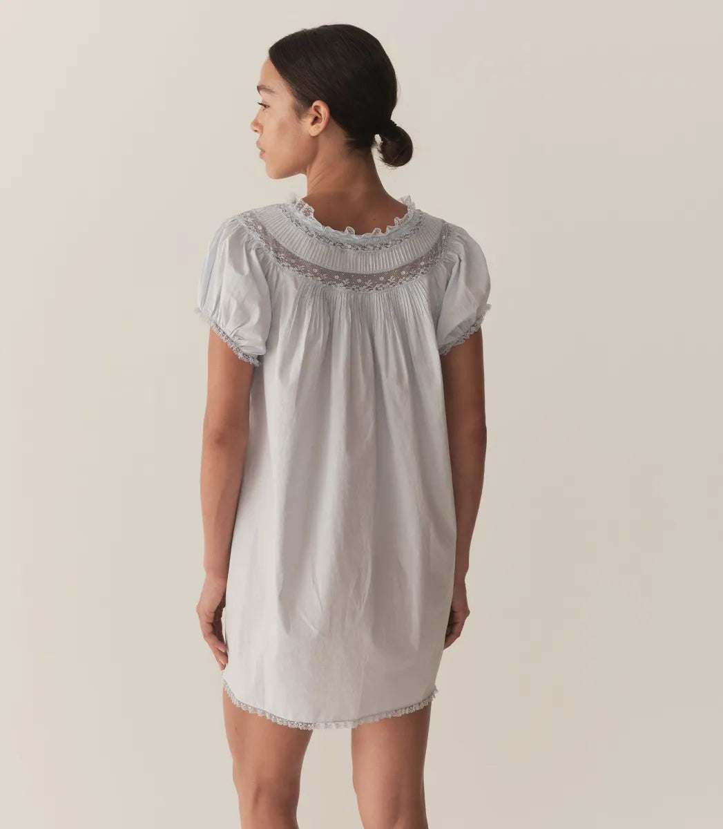 The Daphné Dress by Doen, crafted from crisp organic cotton poplin, offers a refined feminine silhouette with its flattering A-line cut and short puffed sleeves. Featuring delicate floral scallop lace, pintuck accents, and a grosgrain ribbon tie at the neckline, it balances elegance and detail. The scalloped lace trims on the cuffs and hem provide subtle sophistication, making this mini-length dress ideal for warm weather or casual occasions where comfort and style are paramount.