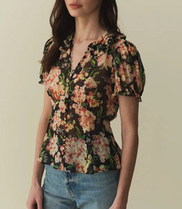 The Alona Top by Doen offers timeless sophistication with its light silk georgette fabric and 1930s-inspired design. Featuring short puffed sleeves and a Peter Pan collar adorned with delicate picot-edged ruffles, this blouse highlights a shirred bust that flows into a breezy, slightly cropped silhouette with a bias-cut hem. Self-covered buttons along the front enhance its refined charm. 