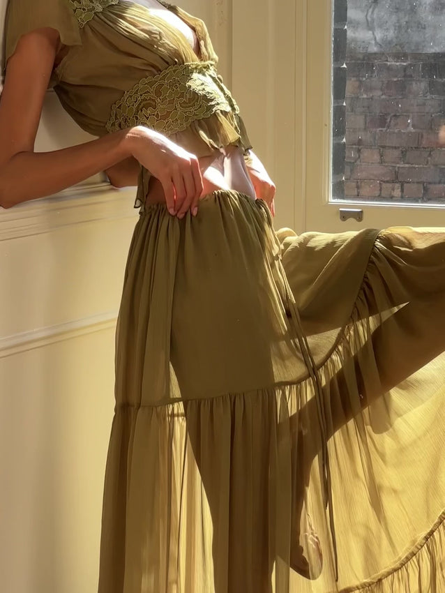 The Sabrina top captures timeless elegance in a soft pistachio chiffon. This vintage-inspired piece features a flattering deep V-neckline with delicately gathered bust detailing that enhances the décolletage. Sheer flutter sleeves provide gentle movement, while a fitted lace bodice defines the waist before transitioning into a subtle peplum hem for added femininity. Self-covered buttons line the centre front for a polished touch, and the lightweight chiffon drapes beautifully across the bodice.